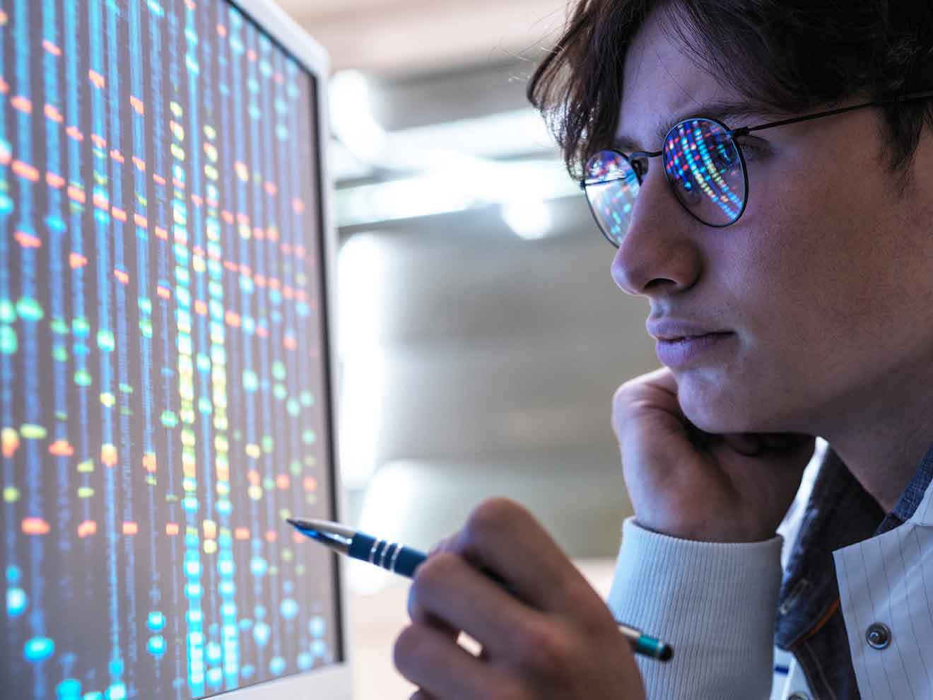 Male teenage expert analyzing DNA through computer at laboratory
