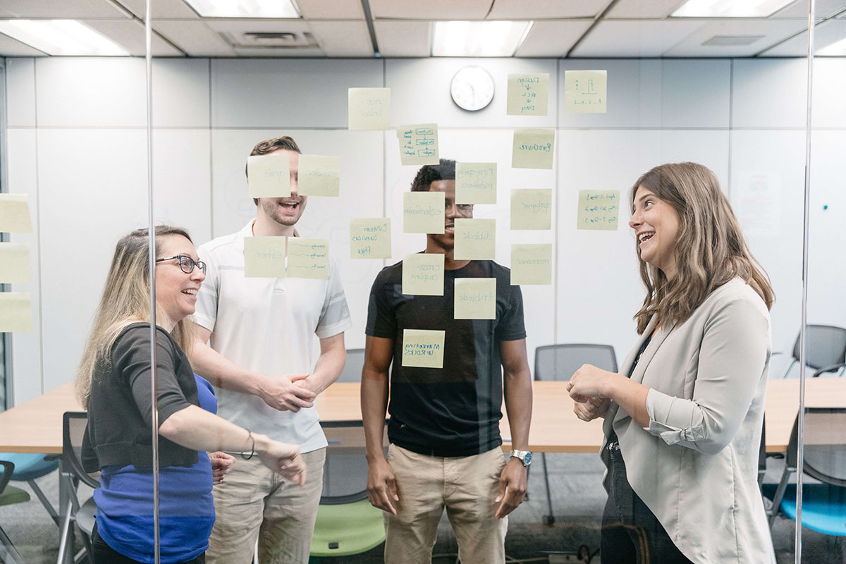 Group discussing project with sticky notes on a glass wall