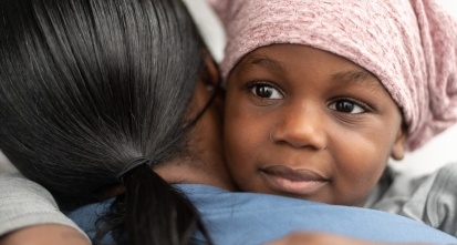 Child with cancer hugs a nurse