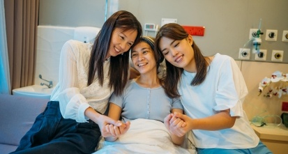 Two Asian female friends visiting her female patient in the hospital ward